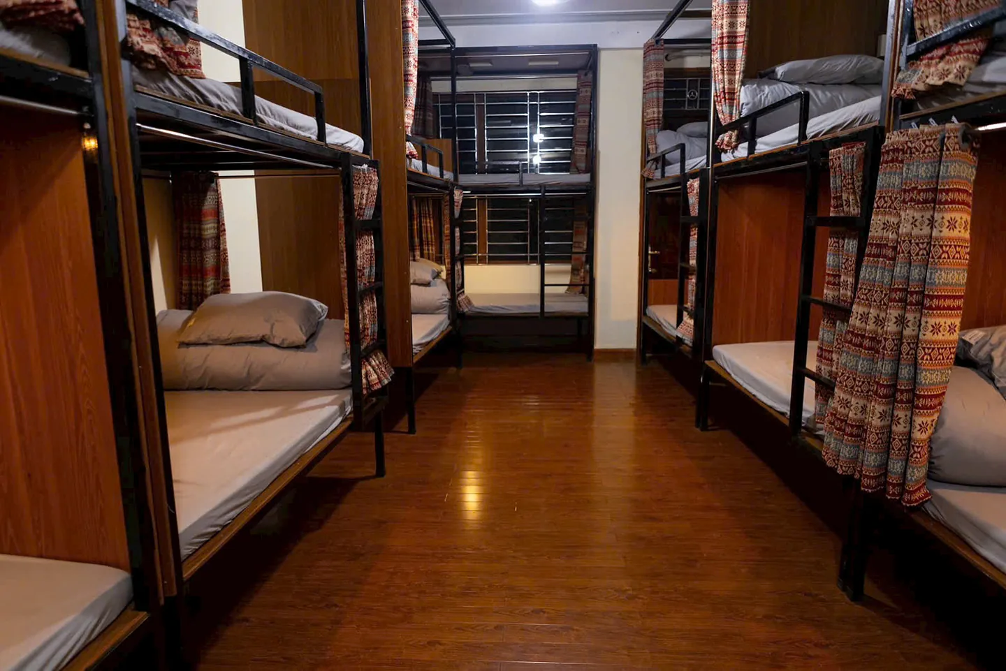 Our hostel dorm: bunk beds with privacy curtains along a wooden floor