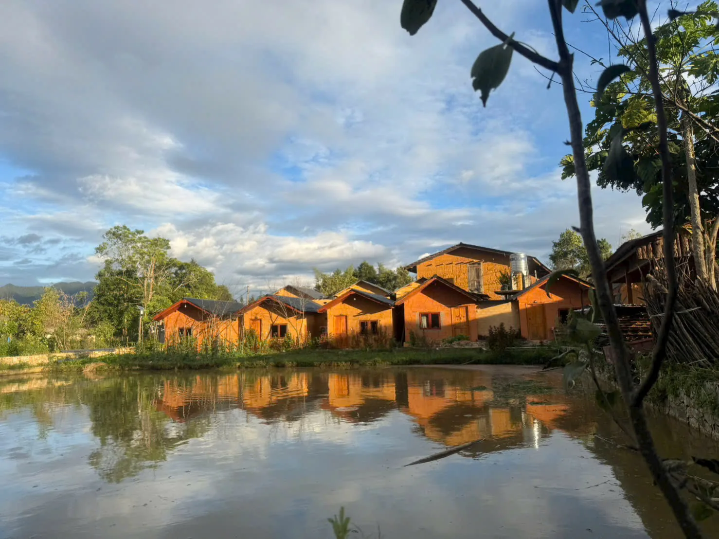 Wooden bungalows reflected in the pond at sunset